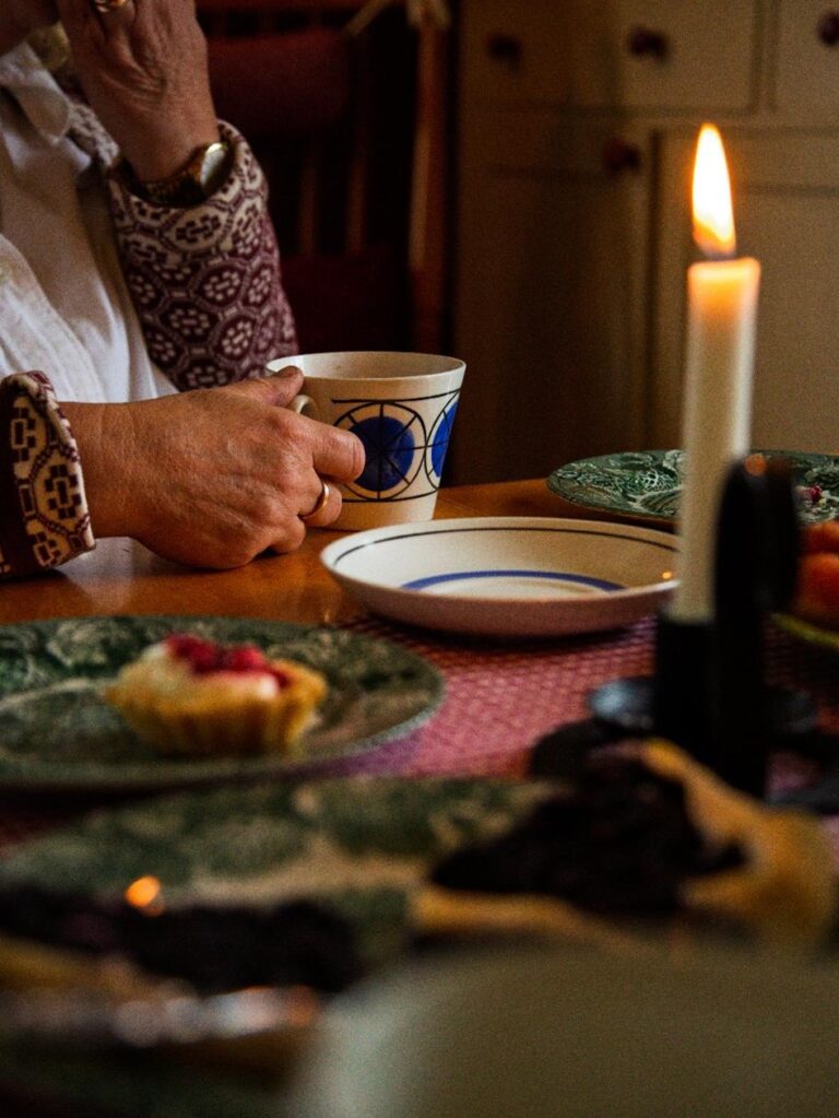 en person håller i kaffekopp vid bord med tänt ljus
