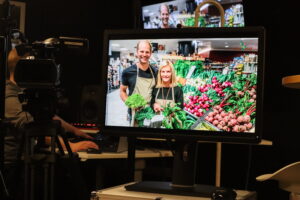 en man och en kvinna visas på tvskärm då de står med grönsaker