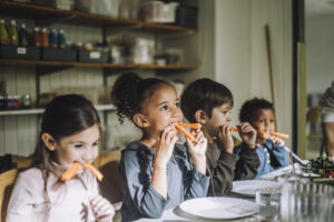Förskolebarn äter morotsstavar.