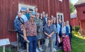 Grupp av människor på trappa framför rött hus.