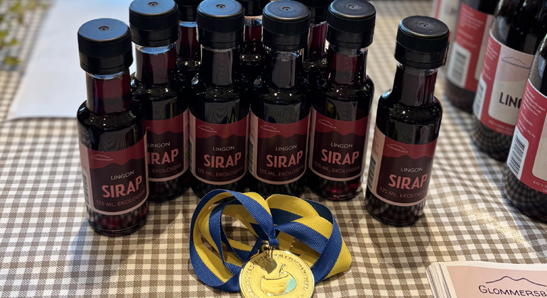 Flaskor med lingonsirap intill en guldmedalj