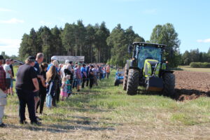 Traktor plöjer och människor tittar på